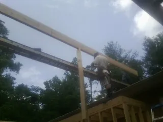 Carpenter setting a ridge beam over a new addition frame — Ice Dam Removal by Roofing Brothers in Hillside