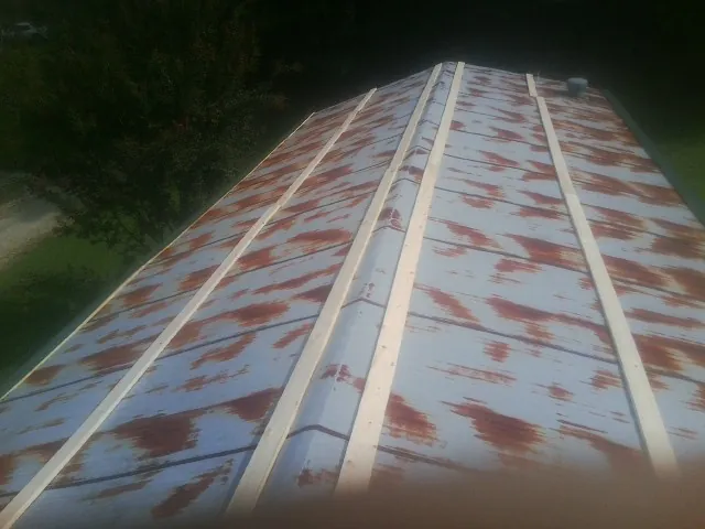 Rusted metal roof panels with new wood purlins before replacement in Hillside