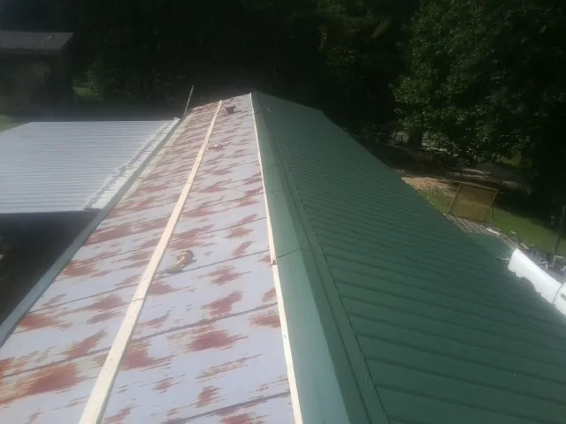 Old rusted panels beside newly installed green metal roofing — Wind Damage Roof Repair by Roofing Brothers in Hillside