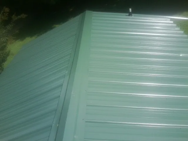 New green metal panels meeting at the ridge of a roof — Flat Roof Repair work by our crew in Hillside