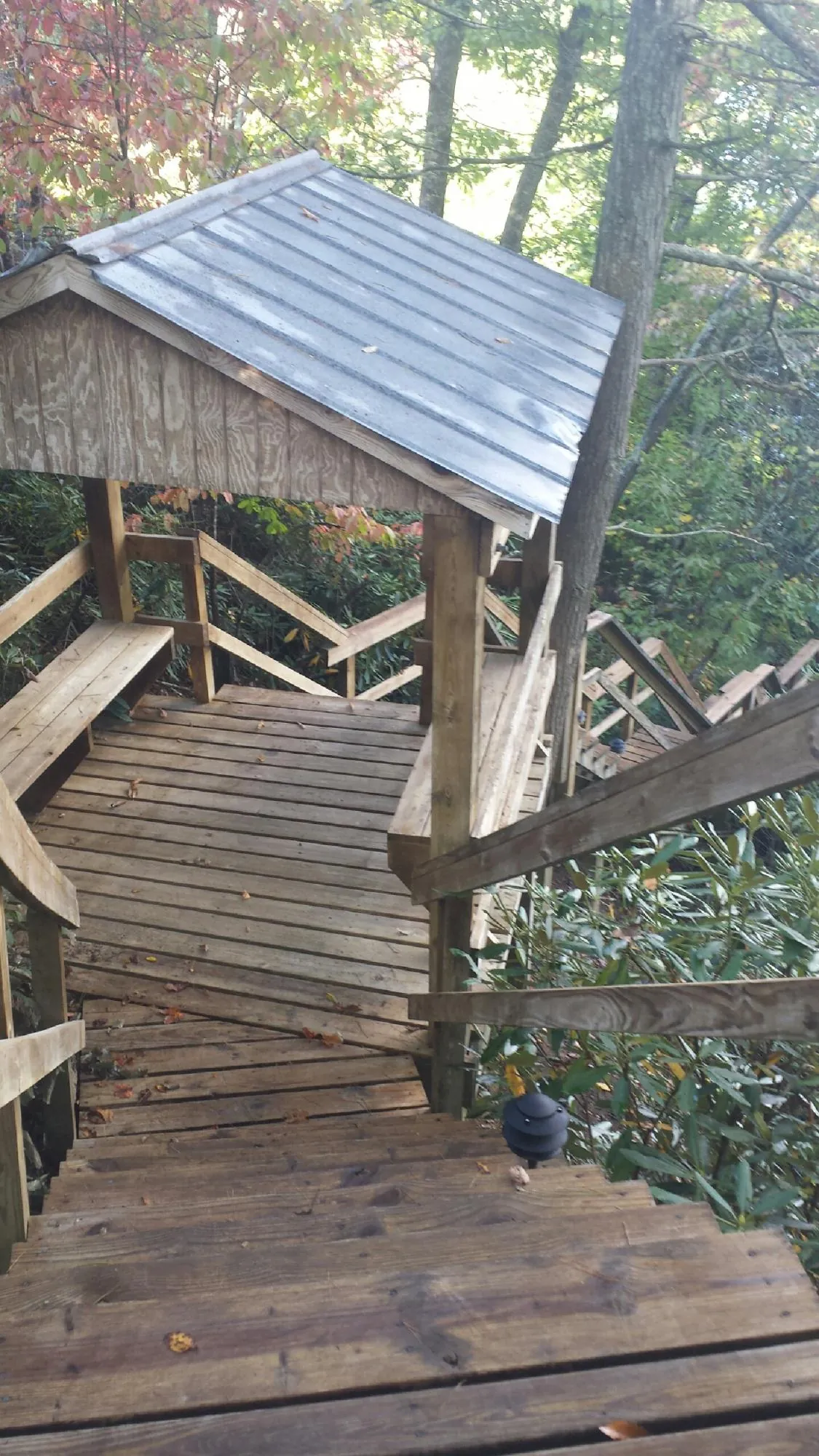 Metal roofed shelter over wooden steps on a wooded walkway — Skylight Repair & Installation work by our crew in Hillside